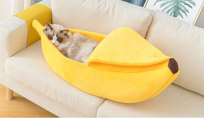 Yellow banana shaped pet bed with cozy cat inside on sofa