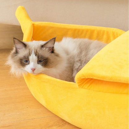 Yellow banana-shaped plush pet bed with a cozy cat lounging inside