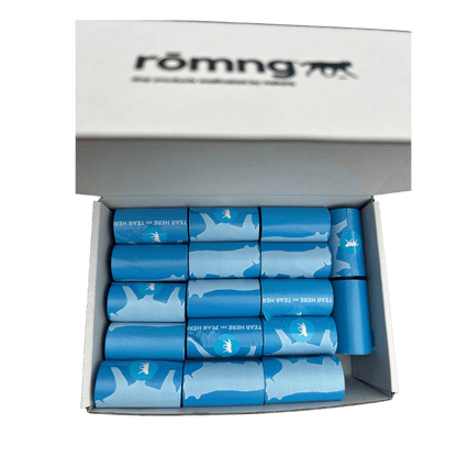 Open box of blue bio-based dog poop bags rolls with white dog silhouettes and tear tab, branded rōmng, eco-friendly pet waste solution