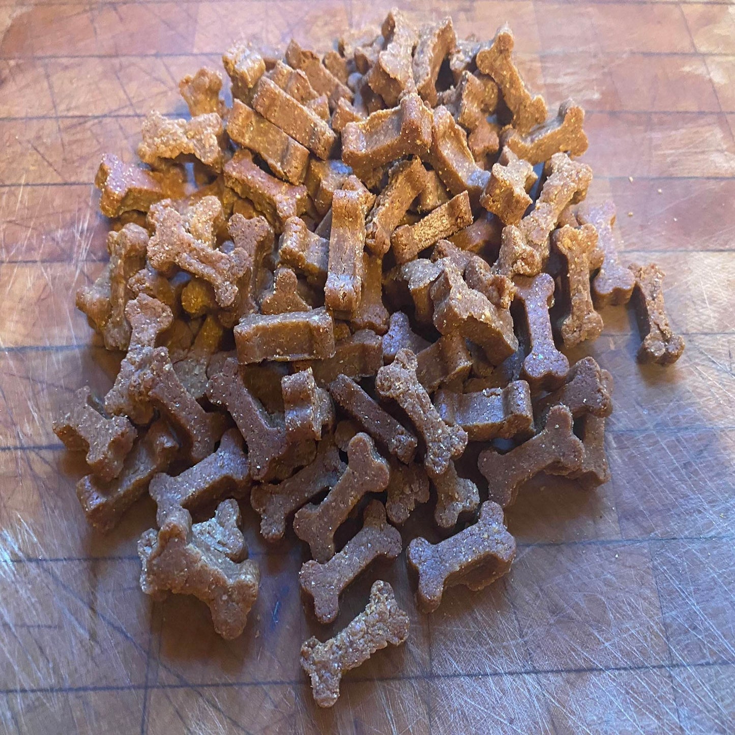 Peanut butter organic dog training treats shaped like small bones on a wooden surface