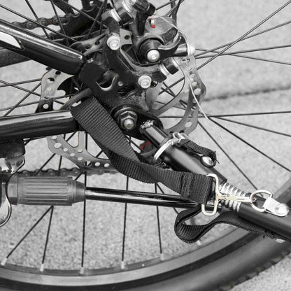 Close-up of black metal bike trailer attachment with strap and spring mechanism connecting to bicycle wheel hub for 2-In-1 pet bike trailer stroller